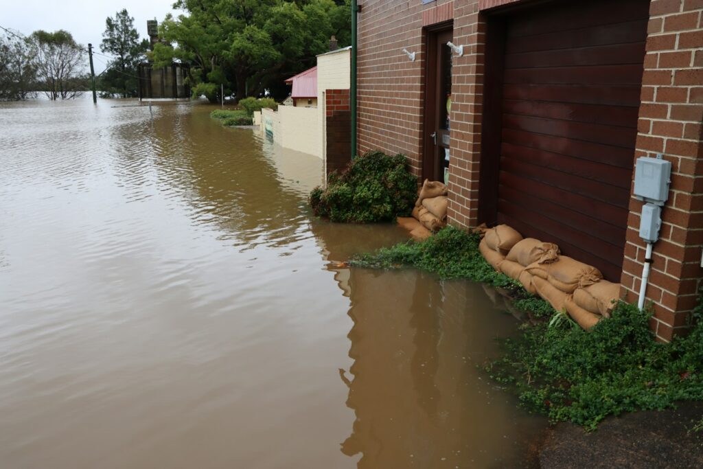 Flood water reaching a brick home protected by sandbags