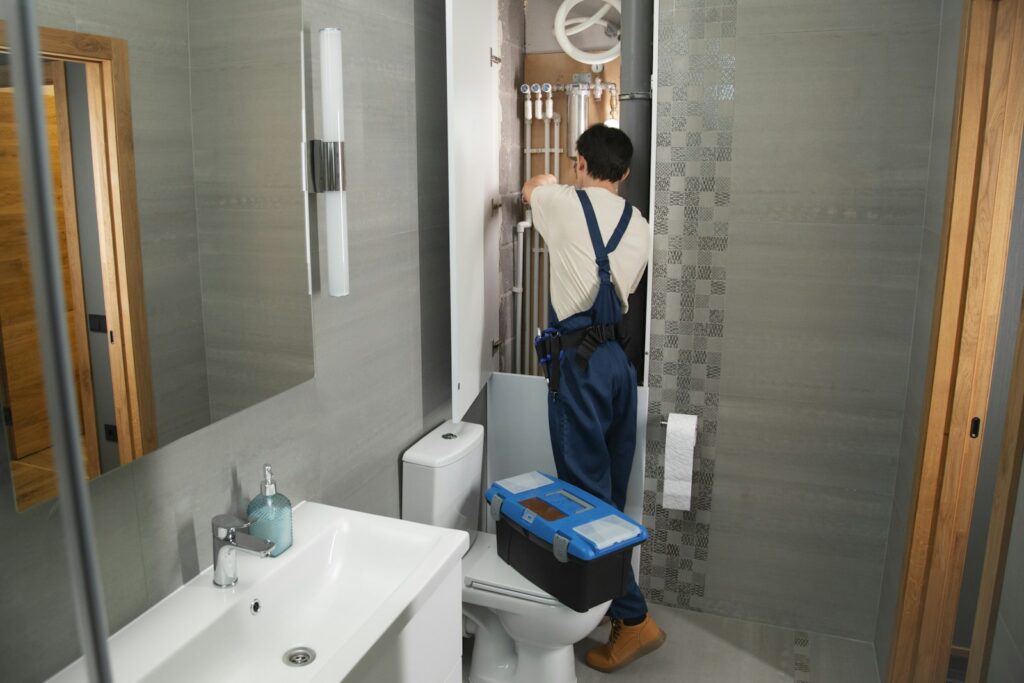 Technician repairing a leaking pipe in a bathroom